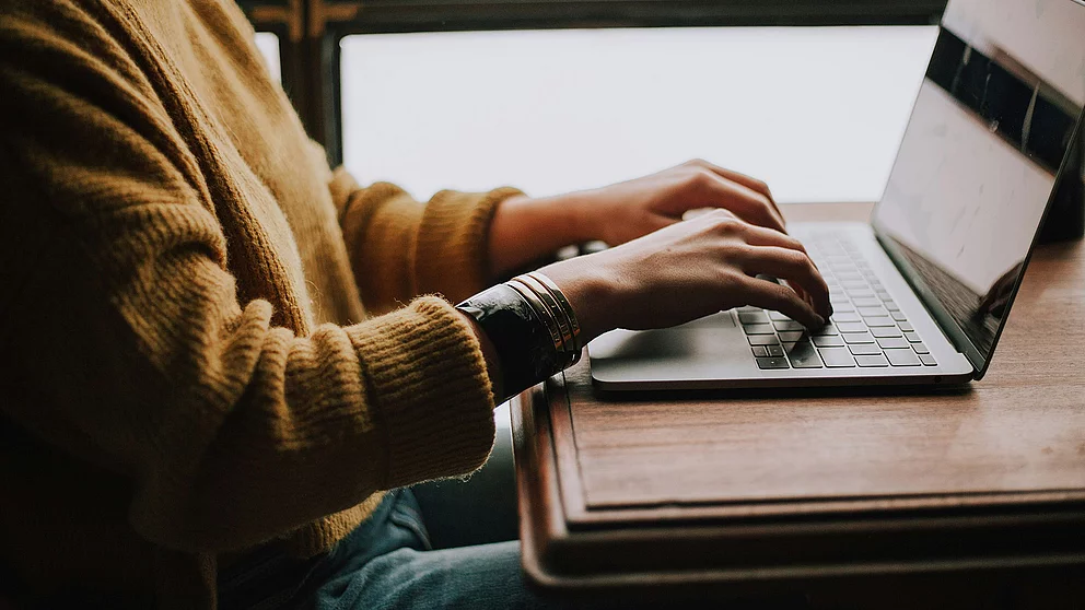 Eine Person sitzt am Computer und gibt etwas ein